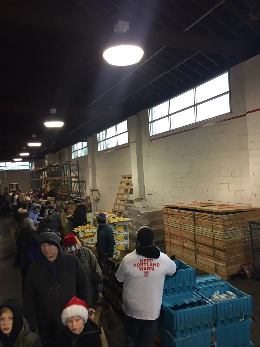 Volunteers in a Weathered Hands packing line, including a volunteer wearing a Keep Portland Warm shirt